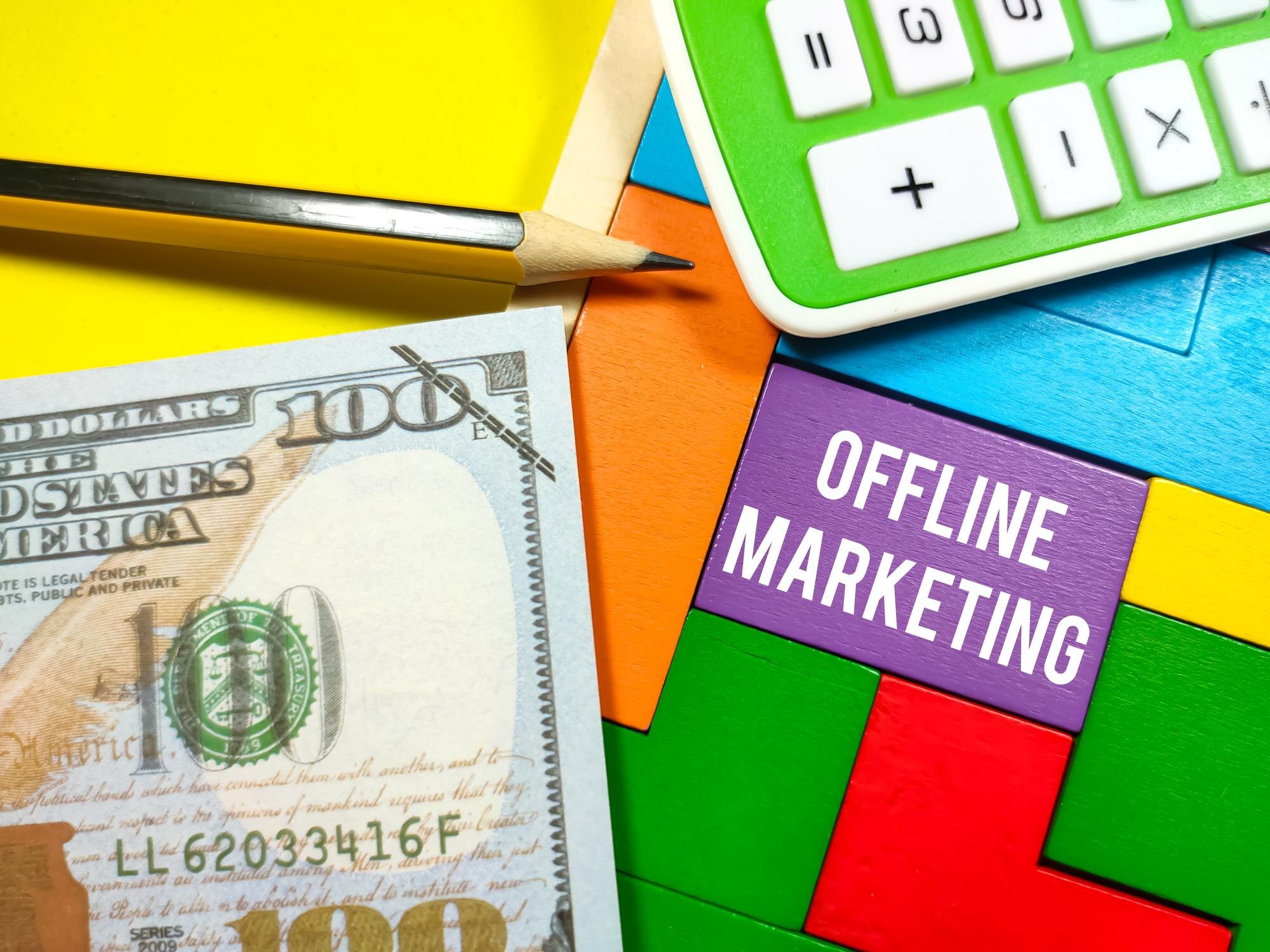 Business ConceptText OFFLINE MARKETING pisanie na drewnianych puzzlach z kalkulatorem i fałszywymi pieniędzmi na żółtym tle