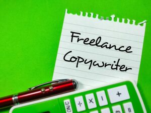 Koncepcja biznesowaTekst niezależny copywriter piszący na papierze firmowym za pomocą pióra i kalkulatora