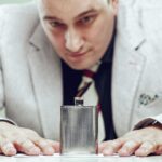 Biznesmen siedzi przy swoim biurku i intensywnie wpatruje się w kolbę umieszczoną przed nim.