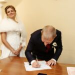 Szczęśliwa, wspaniała panna młoda i stylowy pan młody podpisujący oficjalny dokument ślubny, rejestrujący ceremonię chwili emocjonalnej