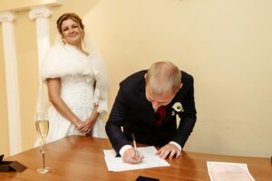 Szczęśliwa, wspaniała panna młoda i stylowy pan młody podpisujący oficjalny dokument ślubny, rejestrujący ceremonię chwili emocjonalnej
