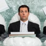 Trzech biznesmenów wygląda zaskoczonych, gdy pływają w biurze pełnym papierów i wody.