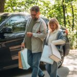 Samochód jest zaparkowany, starsza para idzie razem na świeżym powietrzu w przyrodzie.