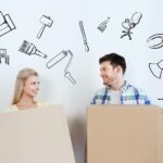 koncepcja domu, ludzi, naprawy i nieruchomości - uśmiechnięta para z dużymi kartonowymi pudełkami przenosi się do nowego miejsca nad bazgrołami