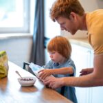 Młody ojciec robi śniadanie dla swojego małego syna