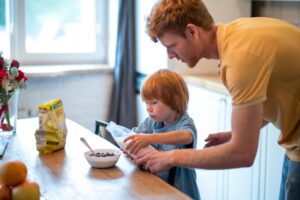 Młody ojciec robi śniadanie dla swojego małego syna