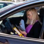 Blond kobieta w średnim wieku w okularach w samochodzie pracuje z dokumentami koncepcja technologii mobilnej