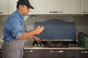 Mężczyzna stoi przed kuchenką gazową ze szczotką w dłoni.