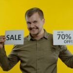 Atrakcyjny mężczyzna pokazujący słowo sprzedaży i pokazujący do 70 procent zniżki na inskrypcję koncepcji Czarnego Piątku