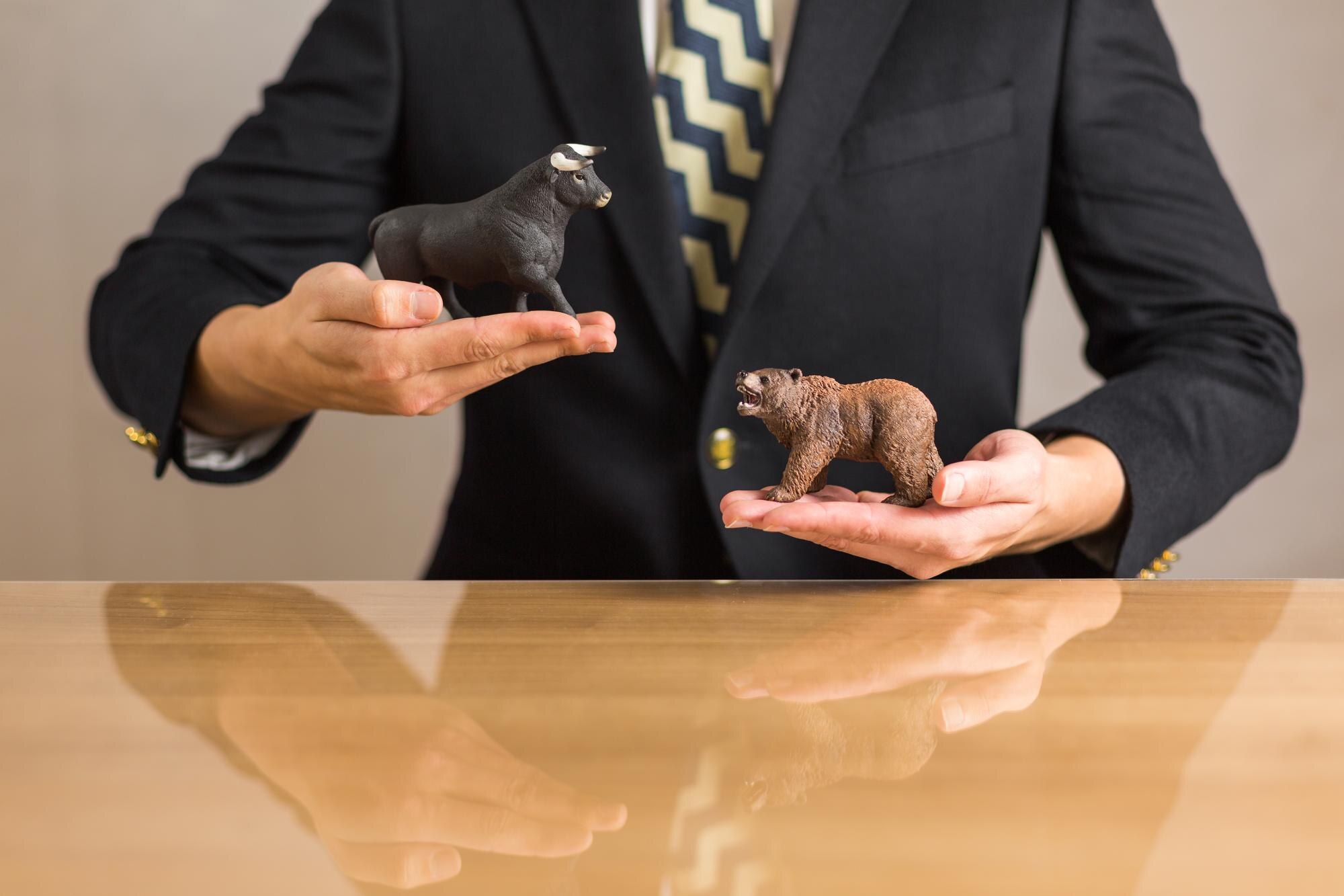 Młody biznesmen trzymający w rękach liczby niedźwiedzia i byka koncepcja rynku byczego i niedźwiedziego