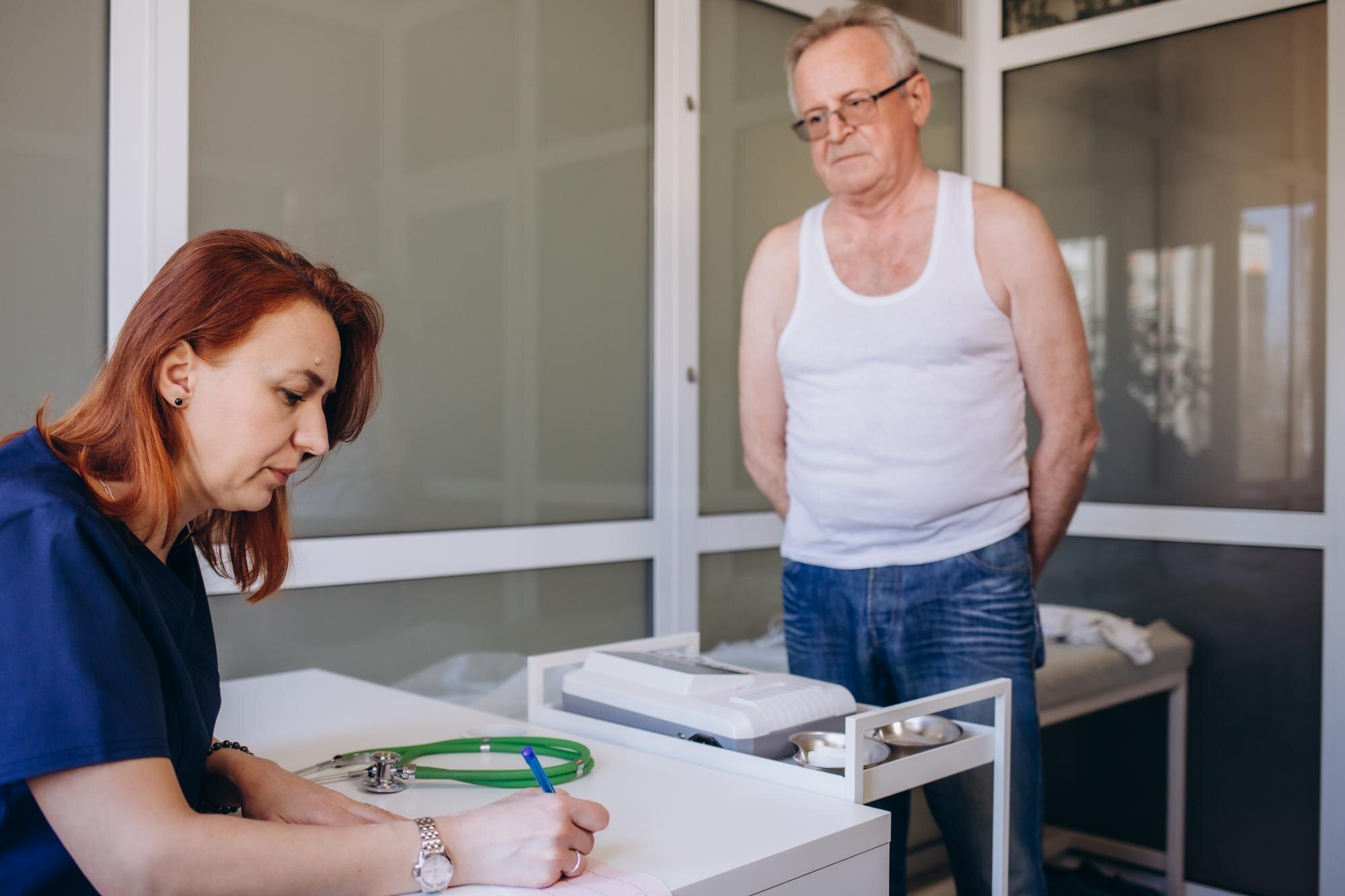 Profesjonalna lekarka pokazująca wynik testu medycznego wyjaśniająca receptę za pomocą aplikacji na tablet cyfrowy odwiedzająca starszego mężczyznę pacjenta w domu siedzącego na kanapie Starsi ludzie koncepcja technologii opieki zdrowotnej