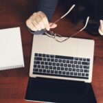 Widok z góry bizneswoman trzymając okulary podczas pracy na laptopie przy biurku