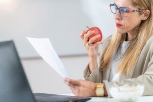 Kobieta żywi się jabłkiem w miejscu pracy