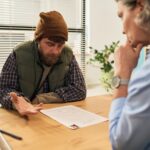Consulting middle aged man during social services meeting with female worker