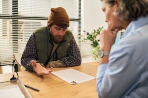 Consulting middle aged man during social services meeting with female worker