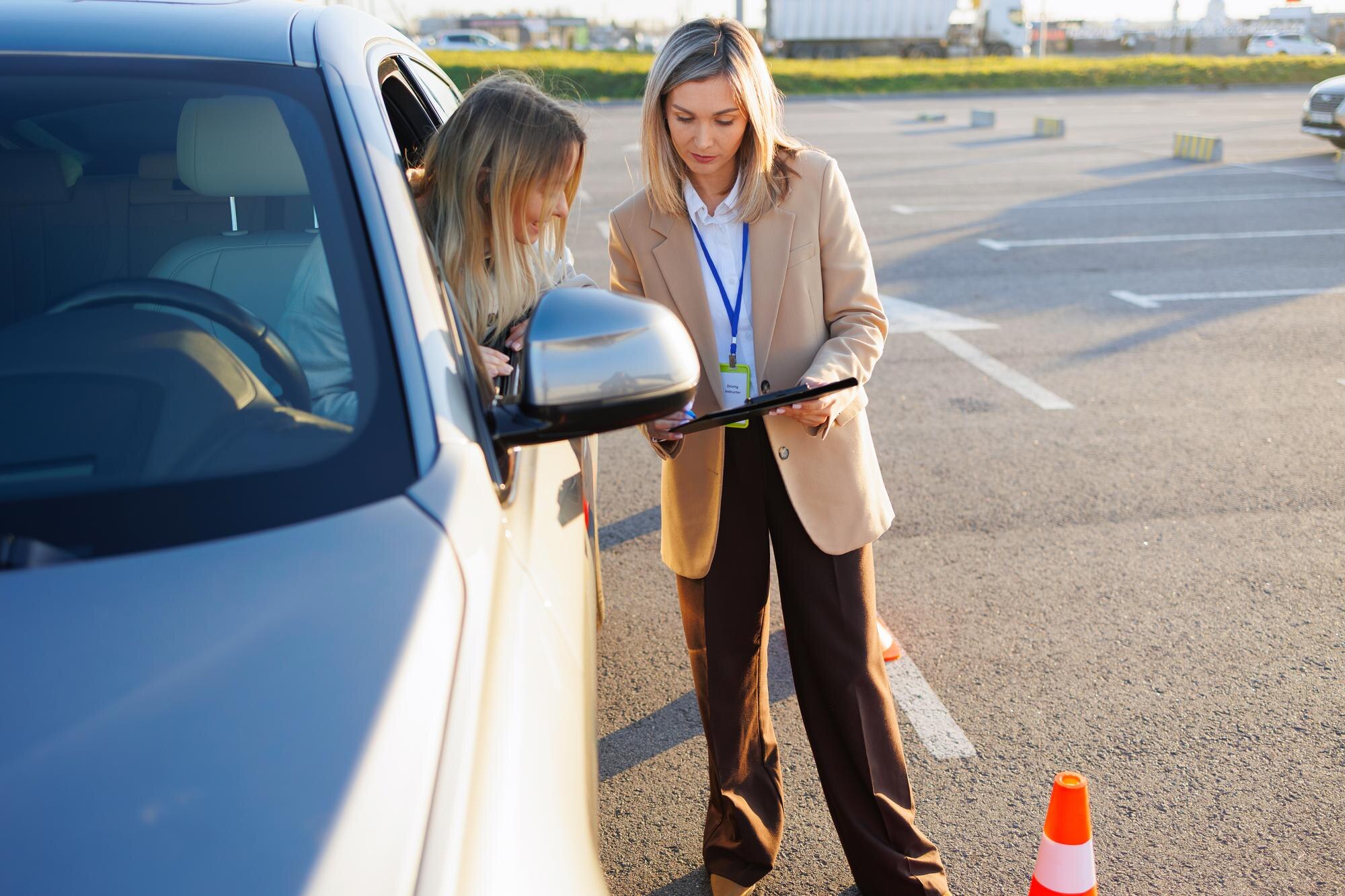 Driving Teacher Reviewing Paperwork with Student Inside Training Car