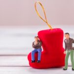 Miniaturowe postacie Biznesmen stojący na podłodze z niewyraźną dekoracją świąteczną