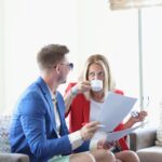 Młoda para rozmawia przy filiżance kawy w kawiarni i przegląda dokumenty biznesowe