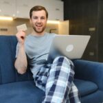 Uśmiechnięty mężczyzna podczas zakupów internetowych w domu