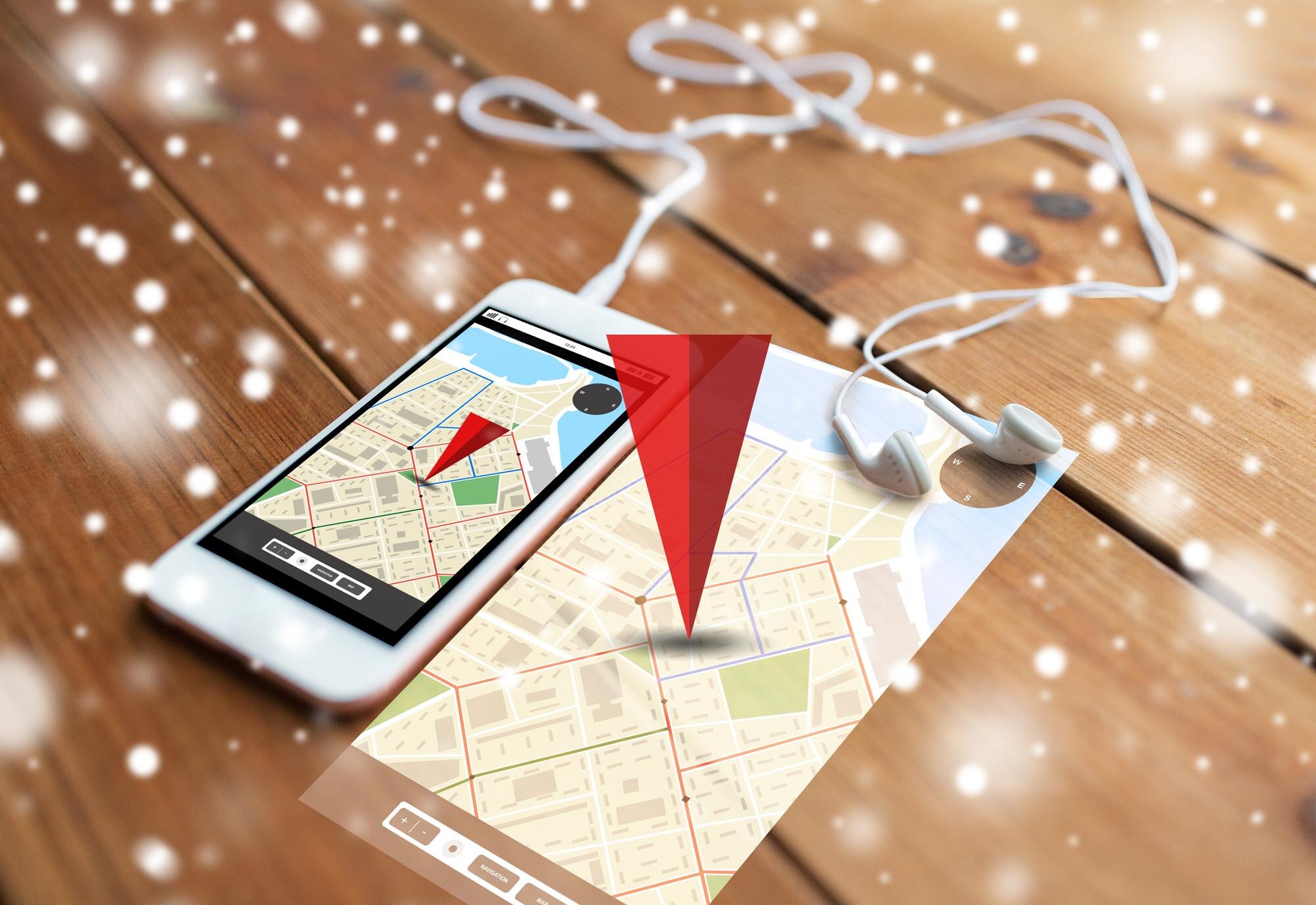 technologia, nawigacja, gadżet i koncepcja obiektu - zbliżenie białego smartfona i słuchawek na drewnianej powierzchni z mapą nawigatora GPS na ekranie