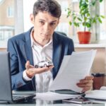 Obsługiwać agenta trzymającego zabawkę samochodową i dokumenty do rejestracji samochodu