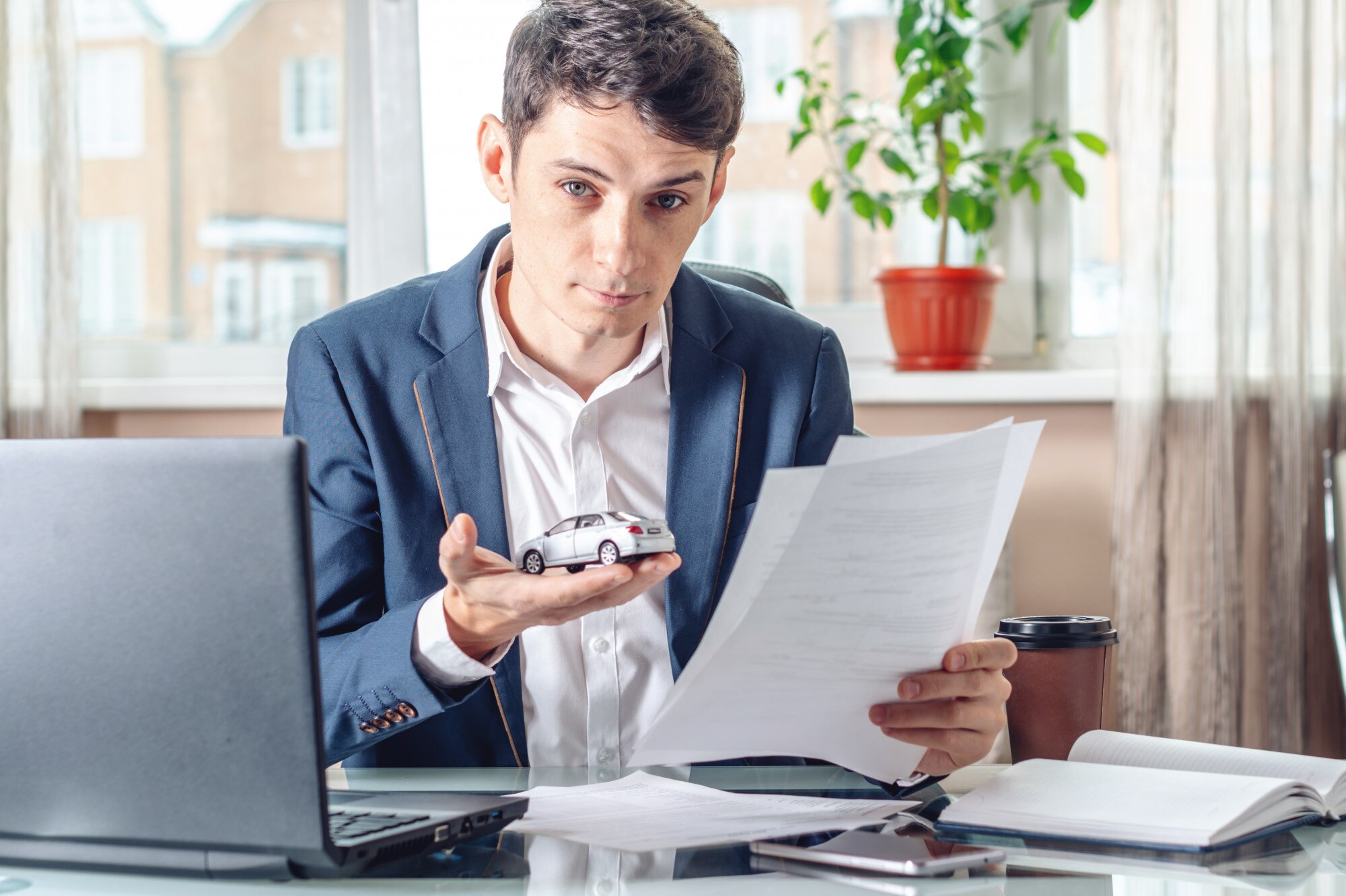 Obsługiwać agenta trzymającego zabawkę samochodową i dokumenty do rejestracji samochodu