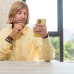 Uśmiechając się z szczęśliwym, pewnym siebie wyrazem twarzy z ręką na podbródku