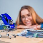 Ładna dziewczyna w okularach wyobraża sobie swój przyszły stylowy samochód siedząc przy stole.
