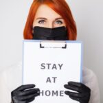 Kobieta trzymająca puste miejsce z napisem zostaje w domu wzywając do zaprzestania rozprzestrzeniania covid-19