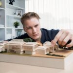 Architekt studiuje model eleganckiego domu, przegląda projekt struktury w celu poprawy z planem budowy na stole Kreatywność i innowacyjność w projektowaniu architektonicznym Iteracja