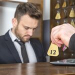 Odcięta ręka mężczyzny dająca klucz do concierge'a na recepcji hotelu