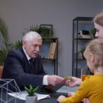 Widok z boku młodej kobiety używającej telefonu komórkowego siedzącej w domu